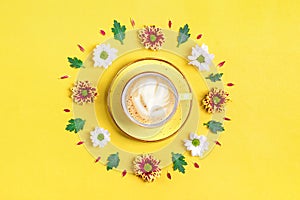 Pattern of flowers of red and white asters, green leaves and a cup of hot coffee cappuccino on yellow background