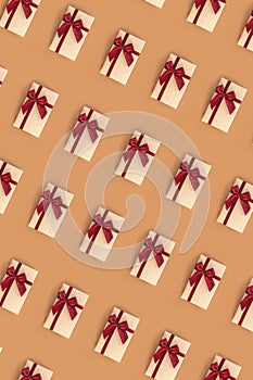 Pattern of gifts in boxes with red bow on beige background