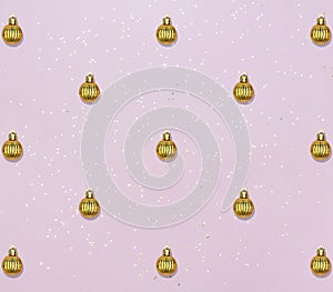 Pattern with golden balls and star confetti on pink pastel background. Christmas or New year card.