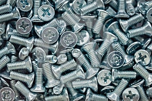 Pattern of a large number of screws. Background of short bolts with a cross-shaped hat