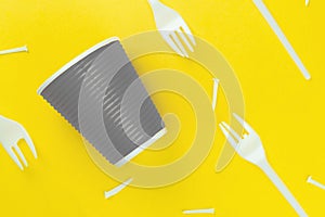Pattern of broken plastic forks, and plastic cup on a yellow background. Ecology problem.