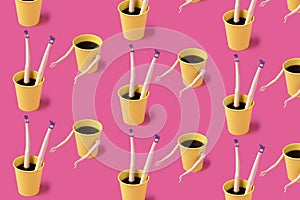 Pattern made of coffee cups with female doll hands and legs on pink background