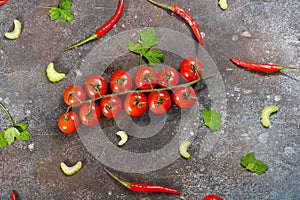 Pattern made of fresh vegetables and branch of cherry tomatoes on dark stone background.
