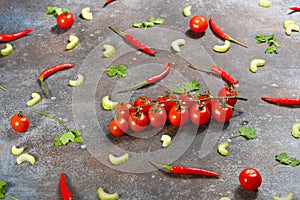 Pattern made of fresh vegetables and branch of cherry tomatoes on dark stone background.
