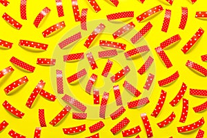 Pattern made from the red pieces of ribbons, isolated on a yellow background. View from the top.