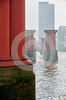 Pattern made from red pillars or columns from original Blackfriars railway bridge in river thames, london on hazy sunny day in