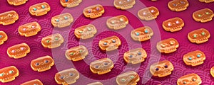 Pattern made of yellow jelly mexican style skulls with colorful glossy eyes on vibrant pink background. halloween dia de