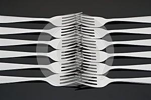 Pattern with many silver forks on black mirror background. Concept,