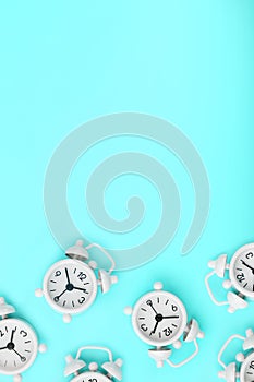 A pattern of many white classic alarm clocks in the form of a pattern on a blue background. Top view with a copy of the space,