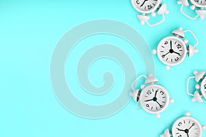 A pattern of many white classic alarm clocks in the form of a pattern on a blue background. Top view with a copy of the space,