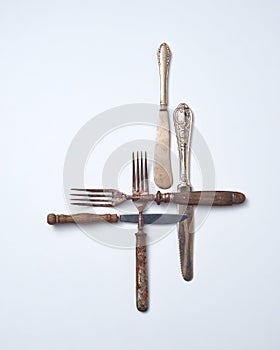Pattern from metalic old knives and forks with wooden handles presented on a gray background with space for text. . Flat