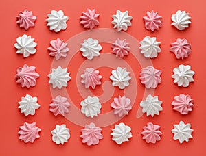 Pattern of pink and white meringues on a red background. Flat lay, Top view