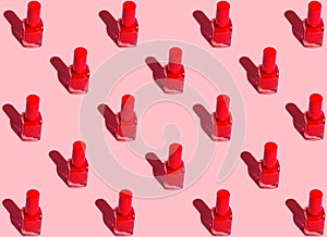 Pattern from red nail polish bottles arranged in symmetrical geometric rows on fuchsia pink background. Pop art style