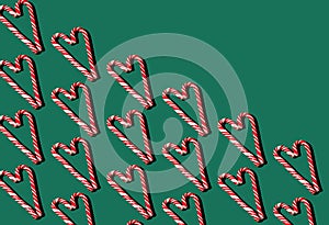 Pattern of red and white lollipops on a green background. Christmas concept. Candy in the shape of a heart. Food