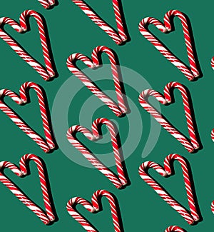 Pattern of red and white lollipops on a green background. Christmas concept. Candy in the shape of a heart. Food