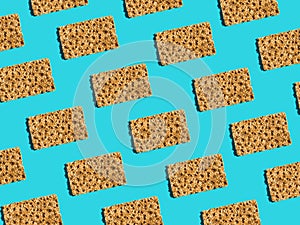 Pattern from scandinavian rye whole grain crispbreads with sesame seeds on solid blue background. Harsh shadows hard light. Trendy