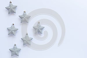 Pattern of silver glittery Christmas star ornaments on white background with copy space