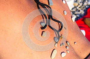 Pattern of small sea stones on women`s skin, pebble beach on a summer day