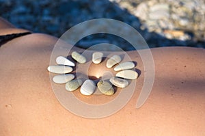 Pattern of small sea stones on women`s skin, pebble beach on a summer day