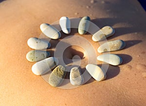 Pattern of small sea stones on women`s skin, pebble beach on a summer day