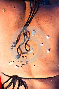 Pattern of small sea stones on women`s skin, pebble beach on a summer day