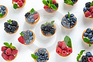 Pattern with tartlets, soft cheese and berries of raspberry, blackberry, blueberry. Delicious and healthy desserts. Photo of