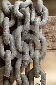 Pattern of thick rusty chain hang on wooden rail