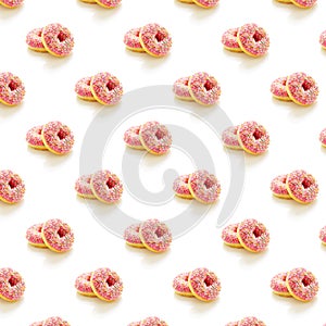 Pattern of two donuts with pink icing and colored sprinkles on a white background