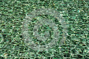 Pattern of wave on green water swimming pool reflecting in the sun