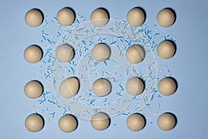 A pattern of white chocolate eggs with one egg tilted slideways on a pale blue background