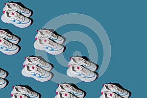 Pattern of white sneakers on a blue background. New sports shoes. Pair of casual fashion accessories.