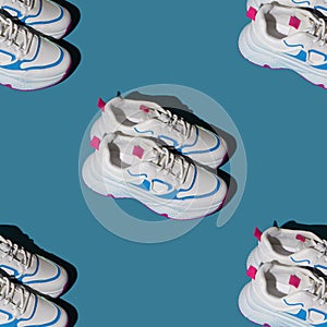 Pattern of white sneakers on a blue background. New sports shoes. Pair of casual fashion accessories