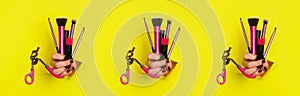 Pattern of woman hands with professional cosmetic tools for make up: brushes, mascara, lipstick, eyelash curler on yellow