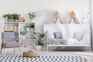 Patterned armchair next to pouf on carpet in child`s bedroom int