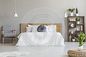 Patterned armchair next to wooden bed in scandi bedroom interior