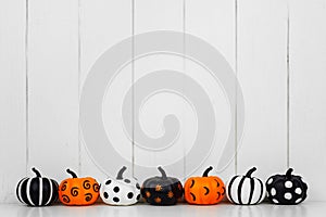 Patterned Halloween pumpkins in a row against a white wood background
