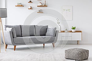 Patterned pouf and grey couch in minimal living room interior wi