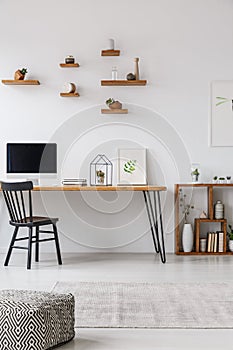 Patterned pouf in minimal workspace interior with black chair at