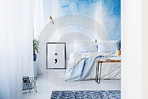 Patterned rug and poster in blue bedroom interior with bed again