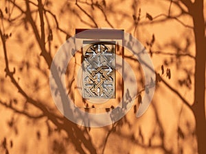Patterned window on a brown wall.
