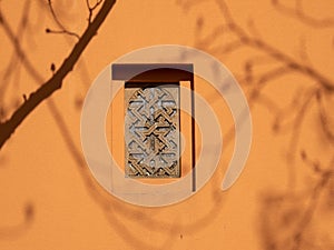 Patterned window on a brown wall.