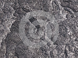 Patterns cracks and shapes emerge from this close up portion of black solidified lava