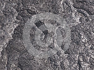 Patterns cracks and shapes emerge from this close up portion of black solidified lava photo
