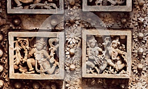 Patterns and dancing people on old walls of stone Hindu temple with fantastic carvings. 12th century, India.