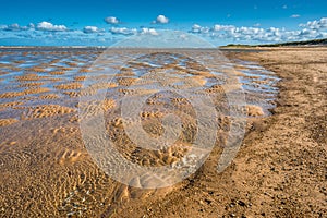Patterns made by tide pools of water at low tide on Barnham Overy Staithe beach