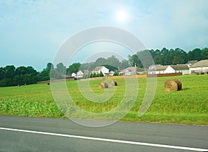 Pature field with hay bales and houses photo