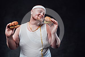 Paunchy man with two hamburgers in his hands and tape measure around his neck