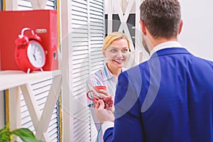 Pause business. Two of attractive business people, standing next to each other, holding a cups, smiling standing at