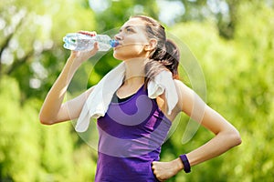 Pause. Recreation of young attractive sporty woman drinking water on nature, park, forest background.