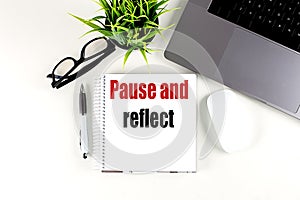 PAUSE AND REFLECT text on notebook with laptop, mouse and pen